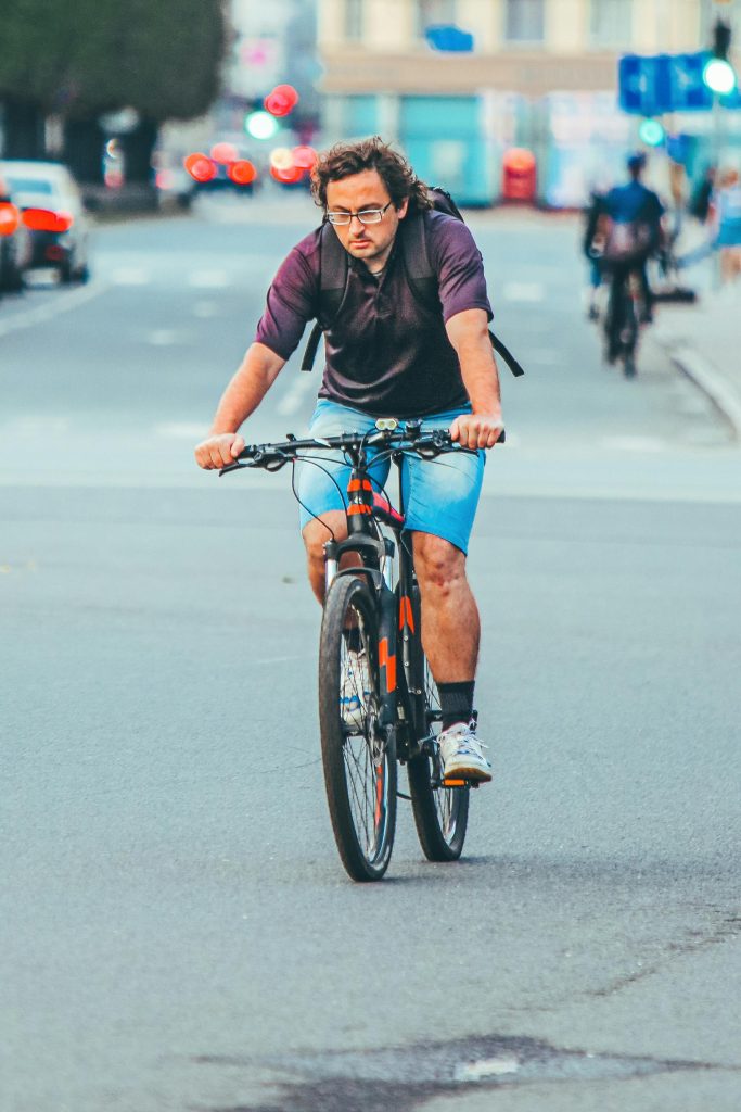 Man cycling on city street in Riga, showcasing urban transportation and active lifestyle.